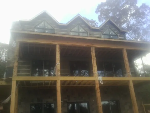 Dormers and porch framing on a large log home under construction — Roof Coating work by our crew in Edinburg